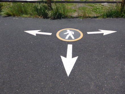Paved walking paths have graphic directional signage stenciled on the surface